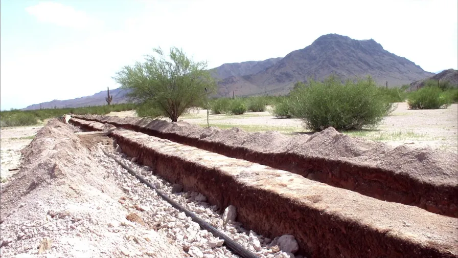 Open drainfield trench with drainrock and distribution pipe on a desert lot in Pinal County, Arizona